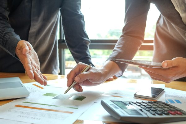 Two office workers are analyzing data.Tablets and pens are in their hands with tablet and graphs on desk,Business concepts.