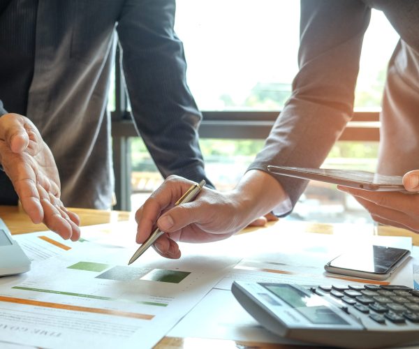 Two office workers are analyzing data.Tablets and pens are in their hands with tablet and graphs on desk,Business concepts.