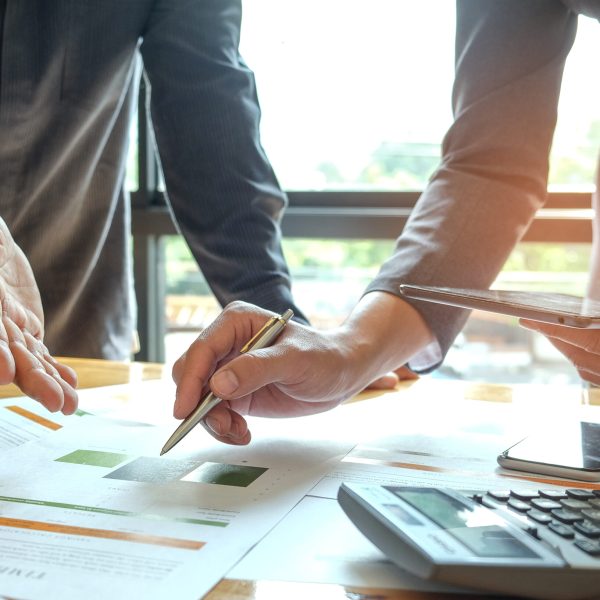 Two office workers are analyzing data.Tablets and pens are in their hands with tablet and graphs on desk,Business concepts.