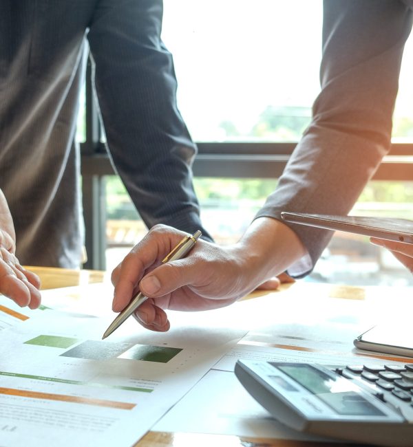 Two office workers are analyzing data.Tablets and pens are in their hands with tablet and graphs on desk,Business concepts.