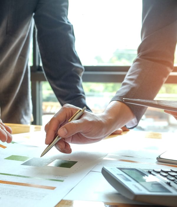Two office workers are analyzing data.Tablets and pens are in their hands with tablet and graphs on desk,Business concepts.